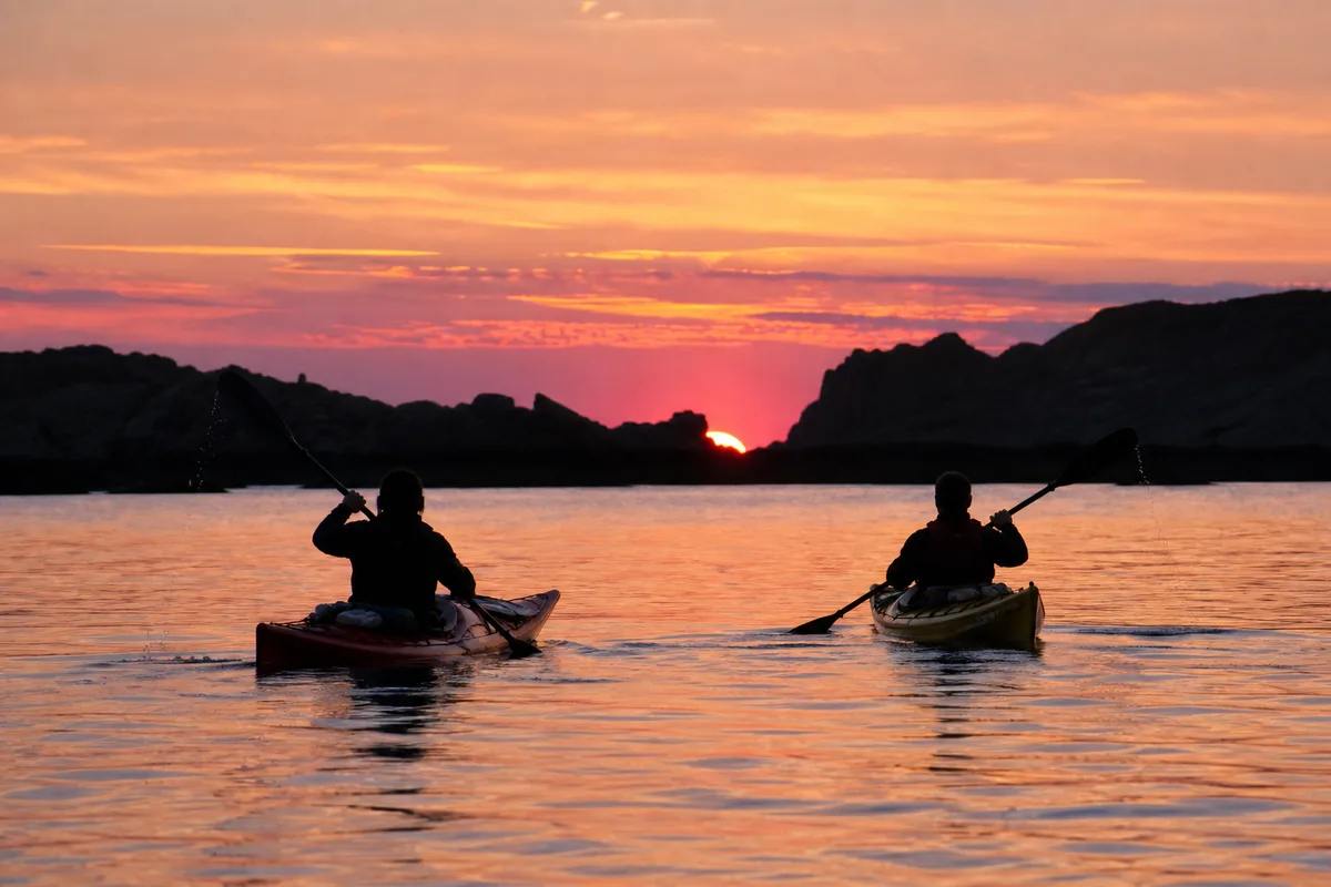 Kayaks progressant sur les eaux calmes de la baie au soleil couchant