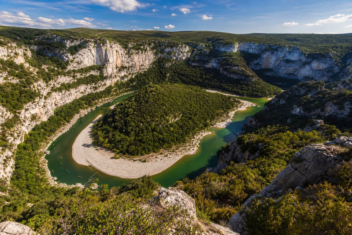 Vue plongeante sur un méandre des gorges de l&rsquo;Ardèche avec canoës minuscules au fond du canyon