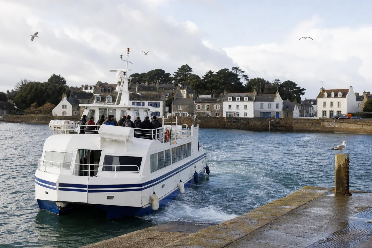 Vedette approchant un petit port insulaire breton, passagers en silhouette sur le pont